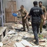 Sur cette photo fournie par le bureau de la police du district, un officier de police verse de l'eau dans une maison en feu dans un quartier chrétien à la suite d'une attaque d'une foule en colère à Jaranwala, près de Faisalabad, au Pakistan.